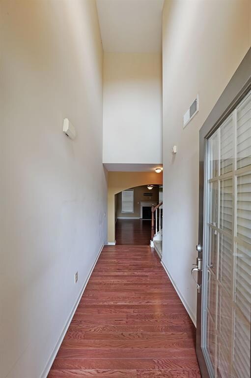 Corridor with wood-type flooring and a towering ce