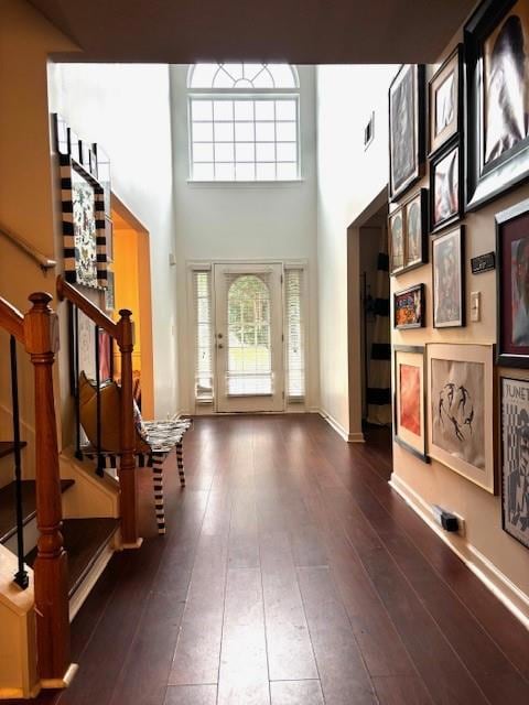Foyer entrance with hardwood / wood-style flooring, stairway, a high ceiling, and healthy amount of natural light