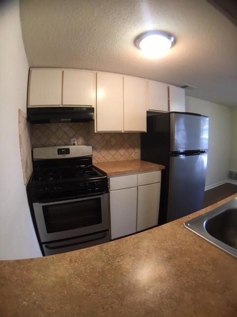 Kitchen with white cabinetry, under cabinet range