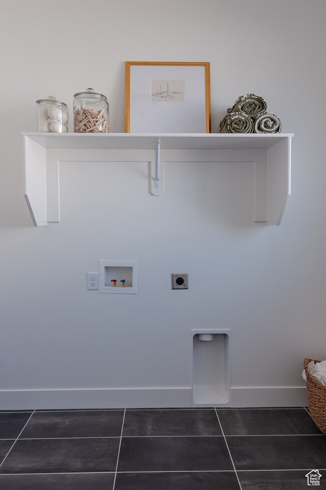Laundry room featuring electric dryer hookup, hookup for a washing machine, and dark tile patterned flooring