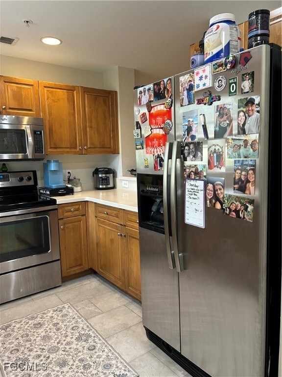 Kitchen featuring brown cabinets, Corian countertops, stainless appliances and recessed lighting.