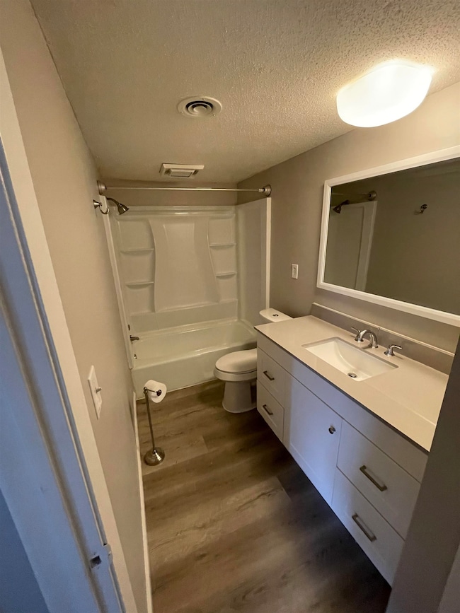 Full bathroom featuring shower / tub combination, a textured ceiling, toilet, vanity, and hardwood / wood-style flooring