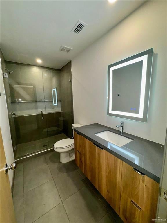 Bathroom with tile flooring, vanity, toilet, and a shower with door