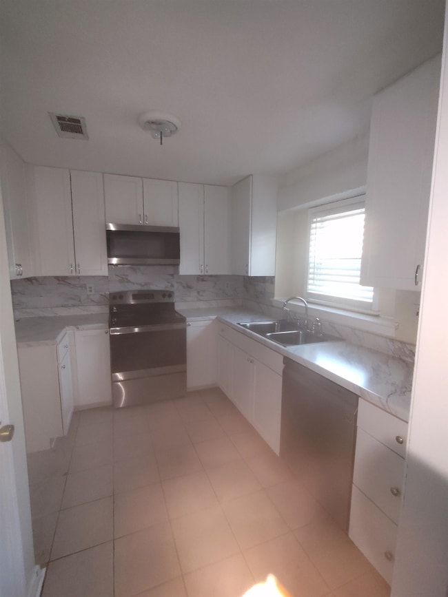 Kitchen with electric range, white cabinets, a sin