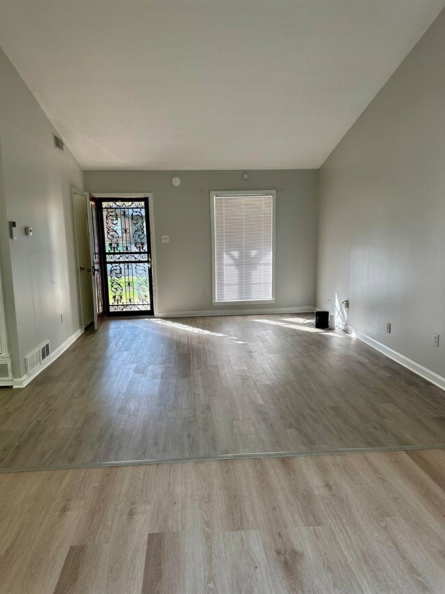 Unfurnished living room with wood finished floors, baseboards, and vaulted ceiling