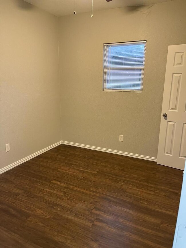 Empty room featuring dark wood-style floors, baseb