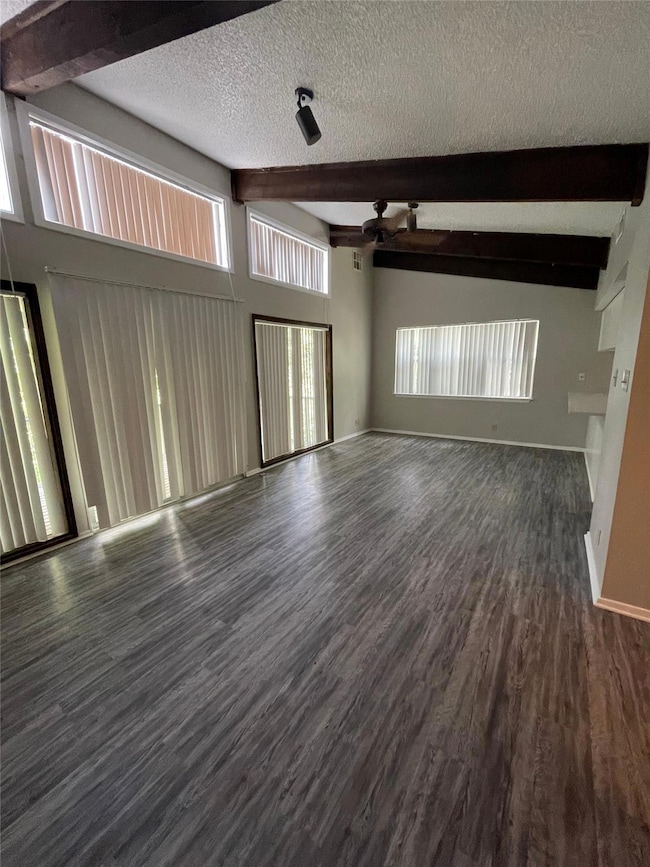 Unfurnished living room with beamed ceiling, a te