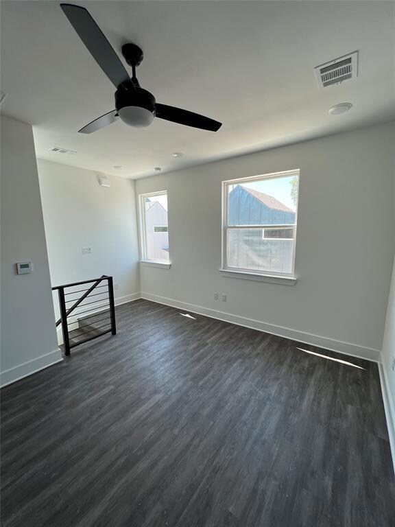Spare room featuring a ceiling fan, dark wood-typ