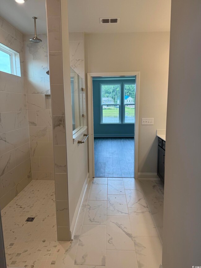 Bathroom with marble look tiles, a walk in shower, and vanity