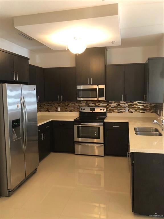 Kitchen with light countertops, backsplash, refrigerator, and stainless steel electric range