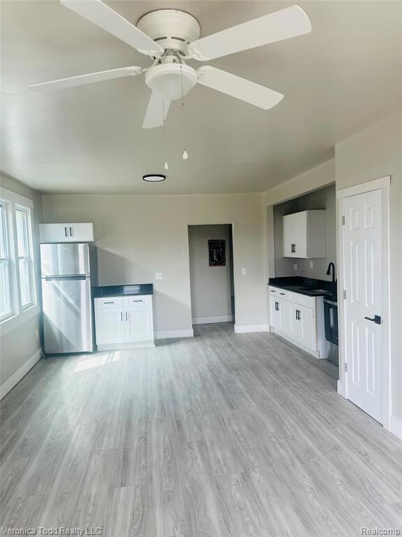 Unfurnished living room featuring light wood-type flooring and ceiling fan