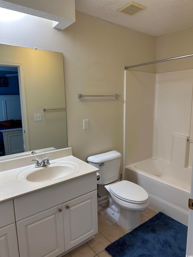 Full bathroom featuring vanity, toilet, tile patterned flooring, shower / bathtub combination, and a textured ceiling
