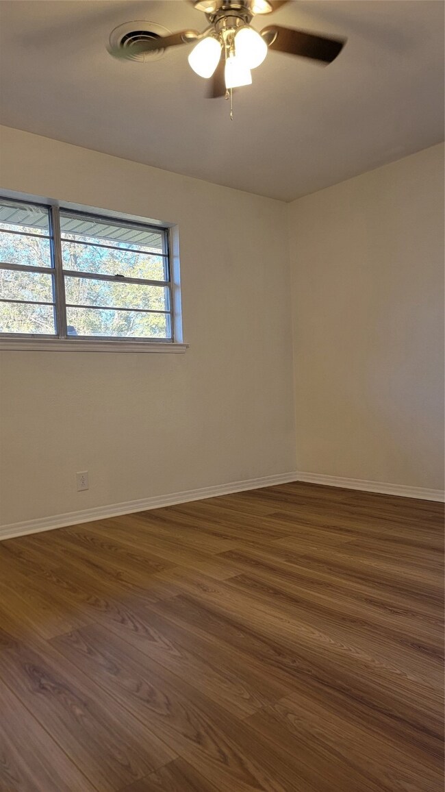 Empty room with dark hardwood / wood-style floors and ceiling fan