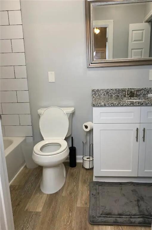 Bathroom with vanity, wood finished floors, toilet, and baseboards