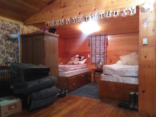Bedroom featuring wood walls, dark wood-style flooring, wooden ceiling, and lofted ceiling