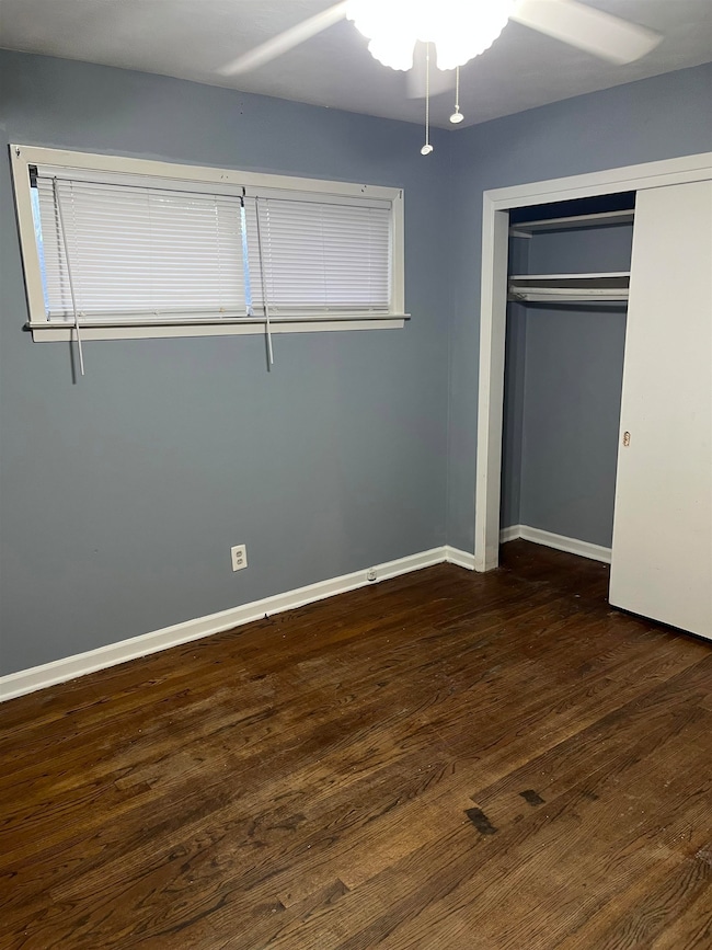 Unfurnished bedroom featuring dark wood-style floors, a closet, and ceiling fan