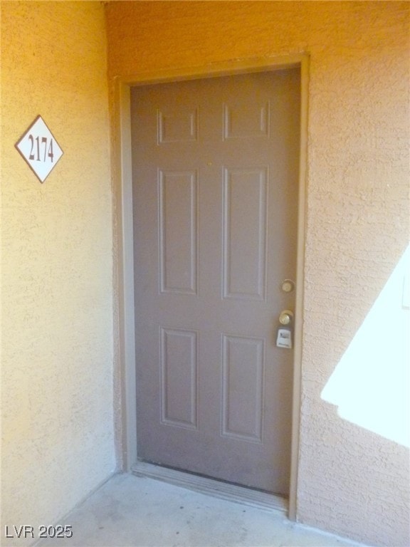 Doorway to property featuring stucco siding