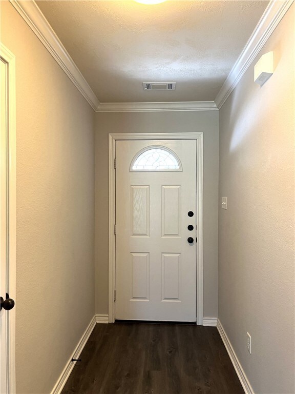 Doorway featuring ornamental molding and dark wood-type flooring