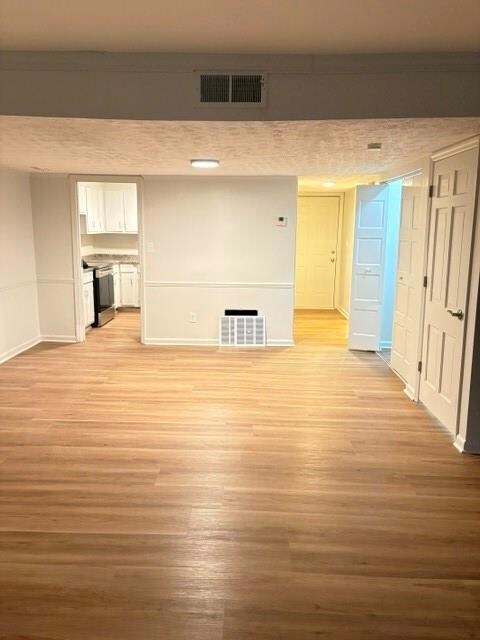 Unfurnished living room with light wood-style flooring and a textured ceiling