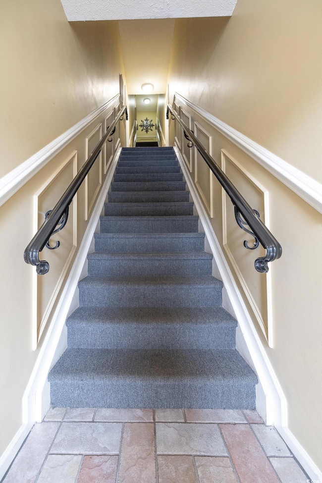Stairs featuring a decorative wall and stone tile floors