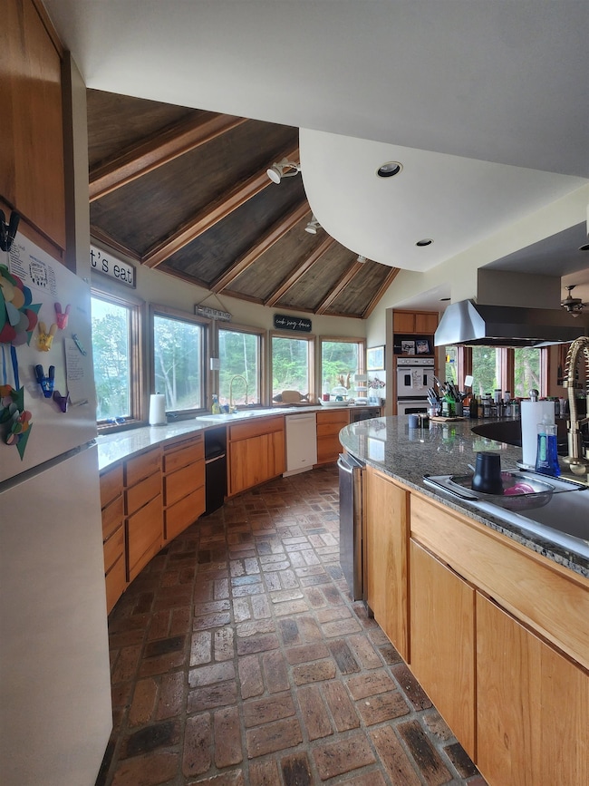 Kitchen with white appliances, brick flooring, vaulted ceiling, recessed lighting, and plenty of natural light