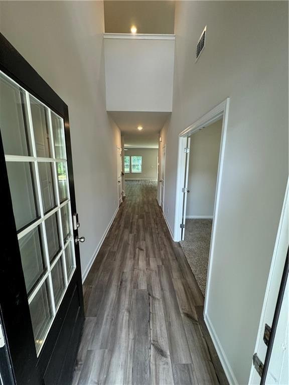 Corridor featuring french doors, dark wood finished floors, and a towering ceiling