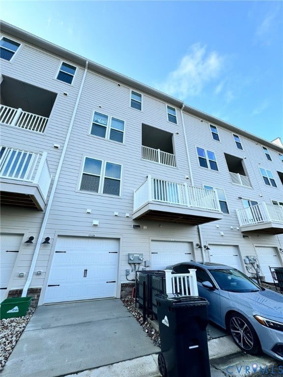 Rear view of property with a balcony and concrete driveway