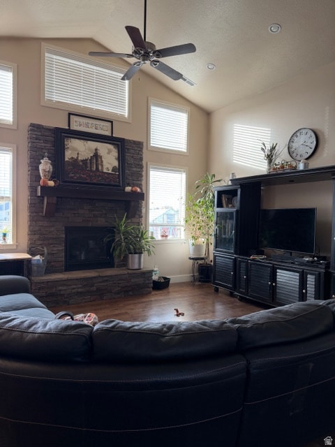 Living room with a ceiling fan, wood finished floors, a fireplace, high vaulted ceiling, and a textured ceiling