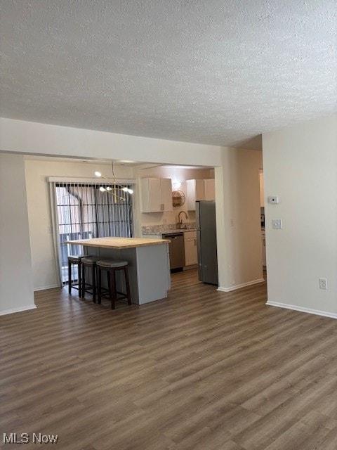 Kitchen with a chandelier, dark wood-style flooring, a breakfast bar, light countertops, and a kitchen island