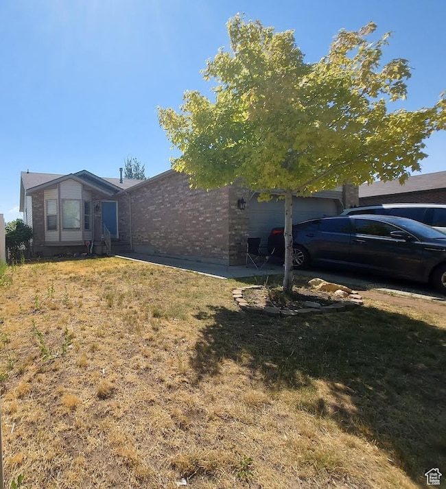 View of property exterior with brick siding, a yard, and an attached garage