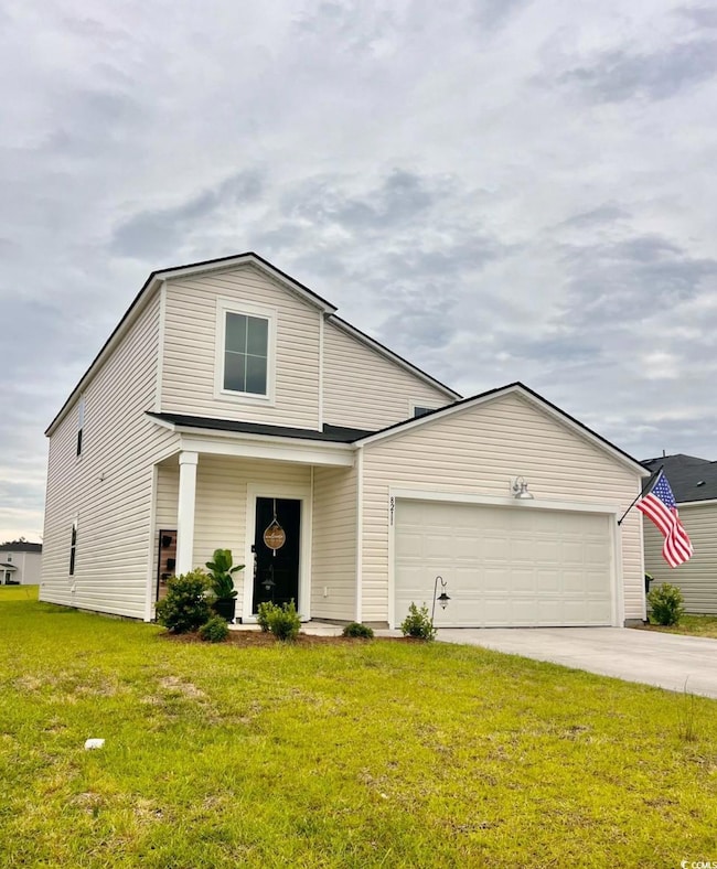 View of front of home with a garage, a front yard, and driveway