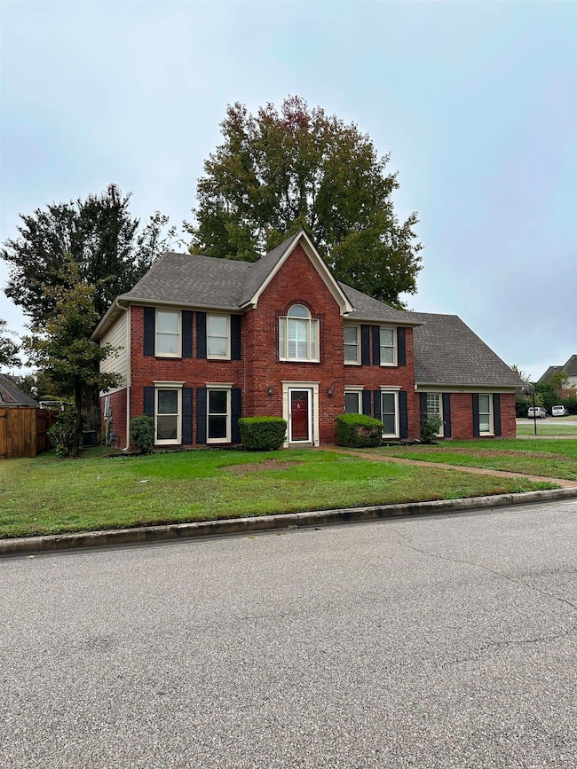 Colonial inspired home with brick siding, a front lawn, and a shingled roof
