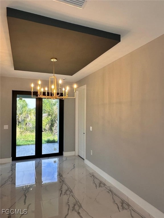 Unfurnished dining area with a raised ceiling, marble tiled flooring, and a chandelier