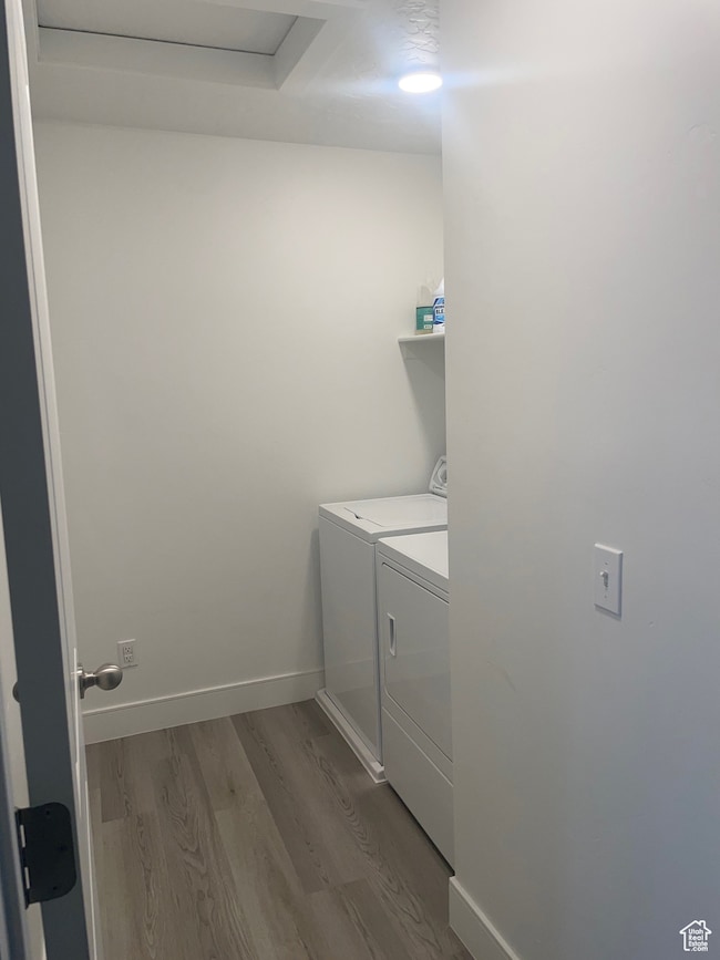 Laundry area with dark wood finished floors and washing machine and clothes dryer