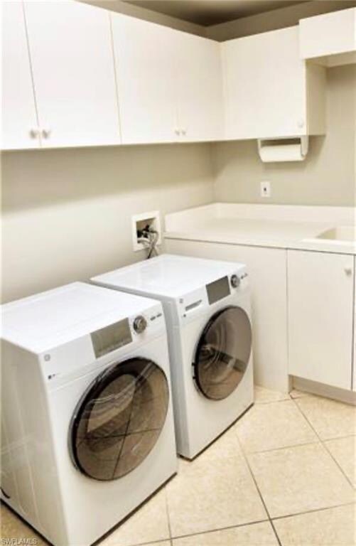 Laundry room featuring cabinet space, light tile patterned flooring, and independent washer and dryer