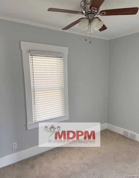 Spare room with light colored carpet, ornamental molding, and a ceiling fan