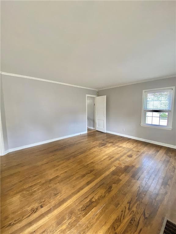 Unfurnished room with ornamental molding and dark wood finished floors