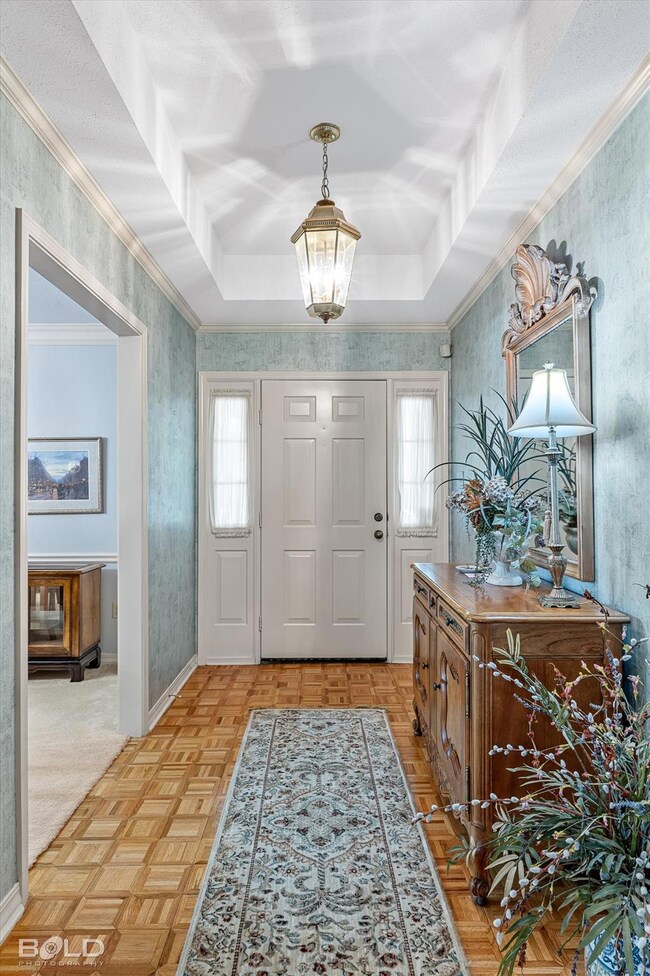 Foyer with light parquet flooring, crown molding, 