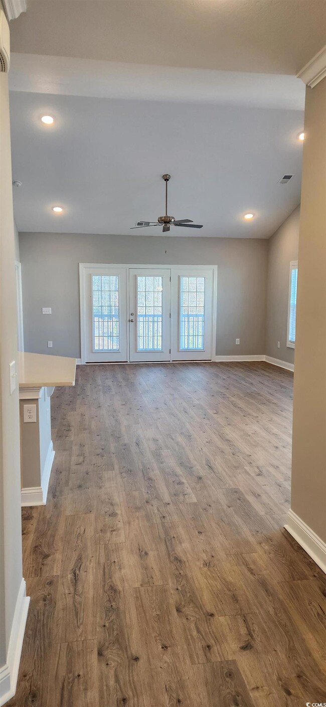 Unfurnished living room featuring ceiling fan, a w