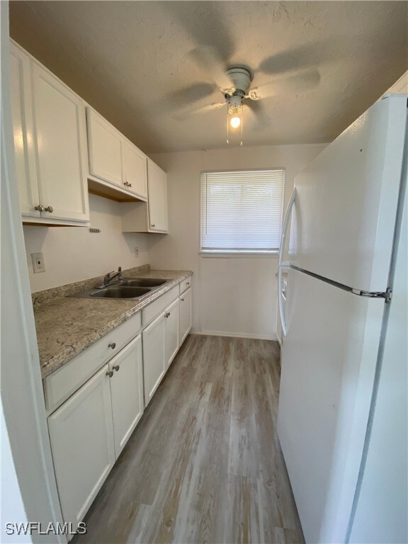 Kitchen with freestanding refrigerator, a sink, li