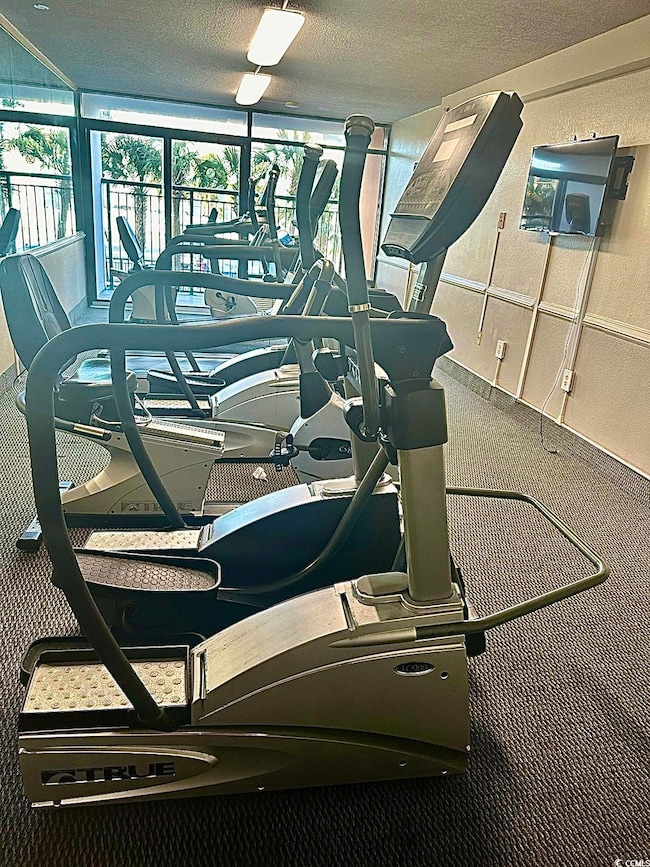 Exercise room with a textured ceiling and carpet f