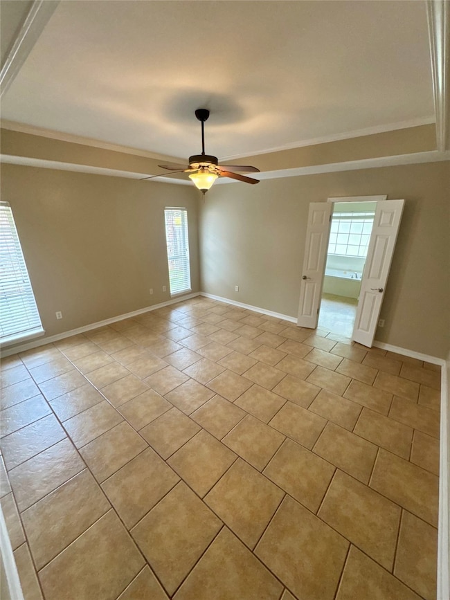 Empty room with healthy amount of natural light, a ceiling fan, and light tile patterned floors