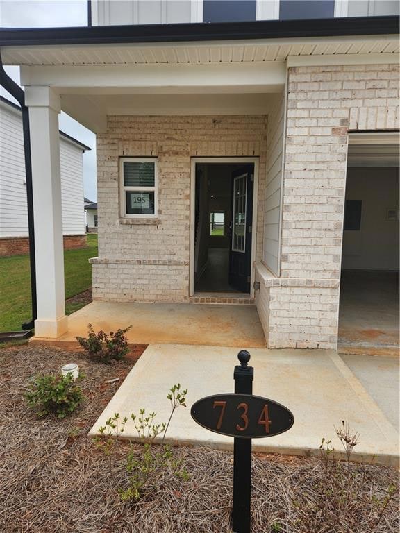 Entrance to property with brick siding and a patio