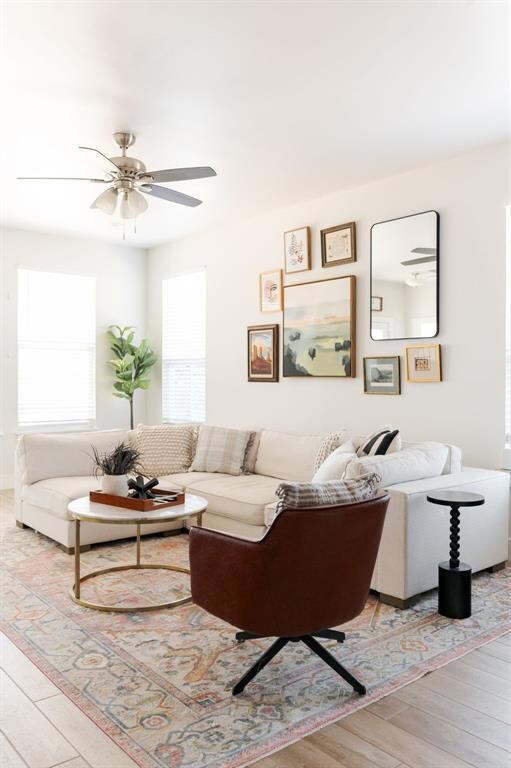 Living room with ceiling fan and light hardwood / 