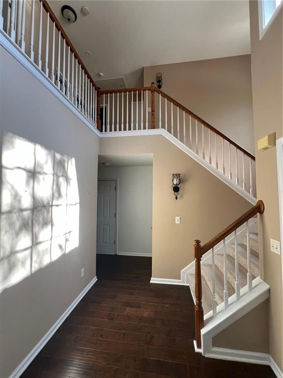 Stairway featuring a towering ceiling and wood finished floors