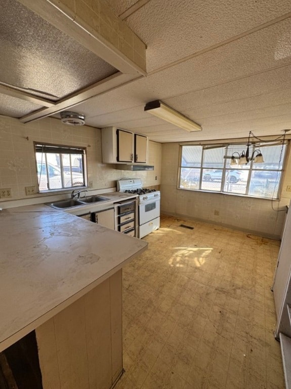 Kitchen with light floors, white gas range, light countertops, and a textured ceiling