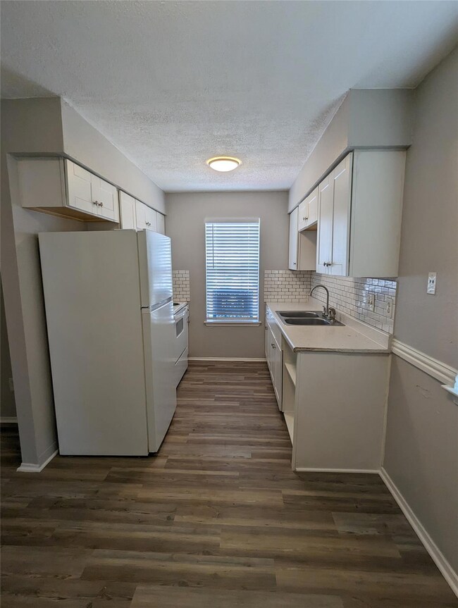 Kitchen with freestanding refrigerator, a sink, l