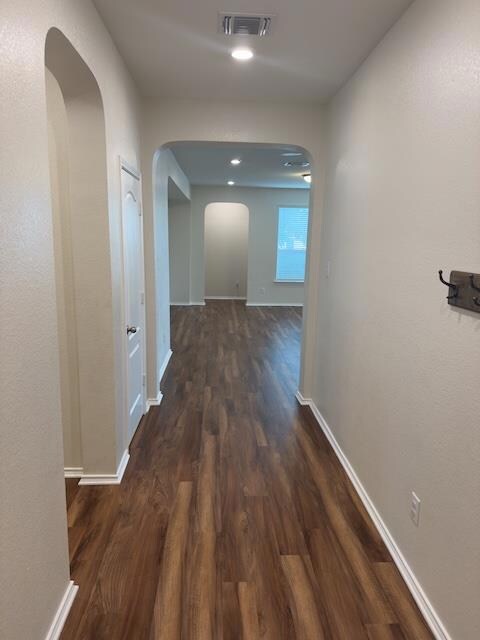 Hallway with arched walkways and wood finished fl