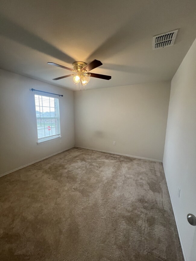 Carpeted empty room with baseboards and a ceiling fan