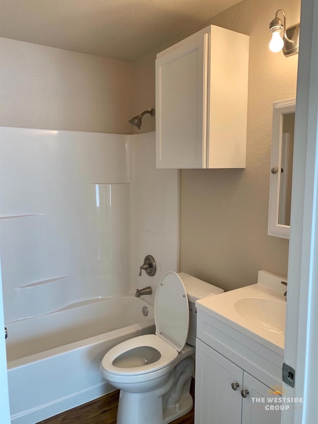 Bathroom with toilet, vanity, wood finished floor